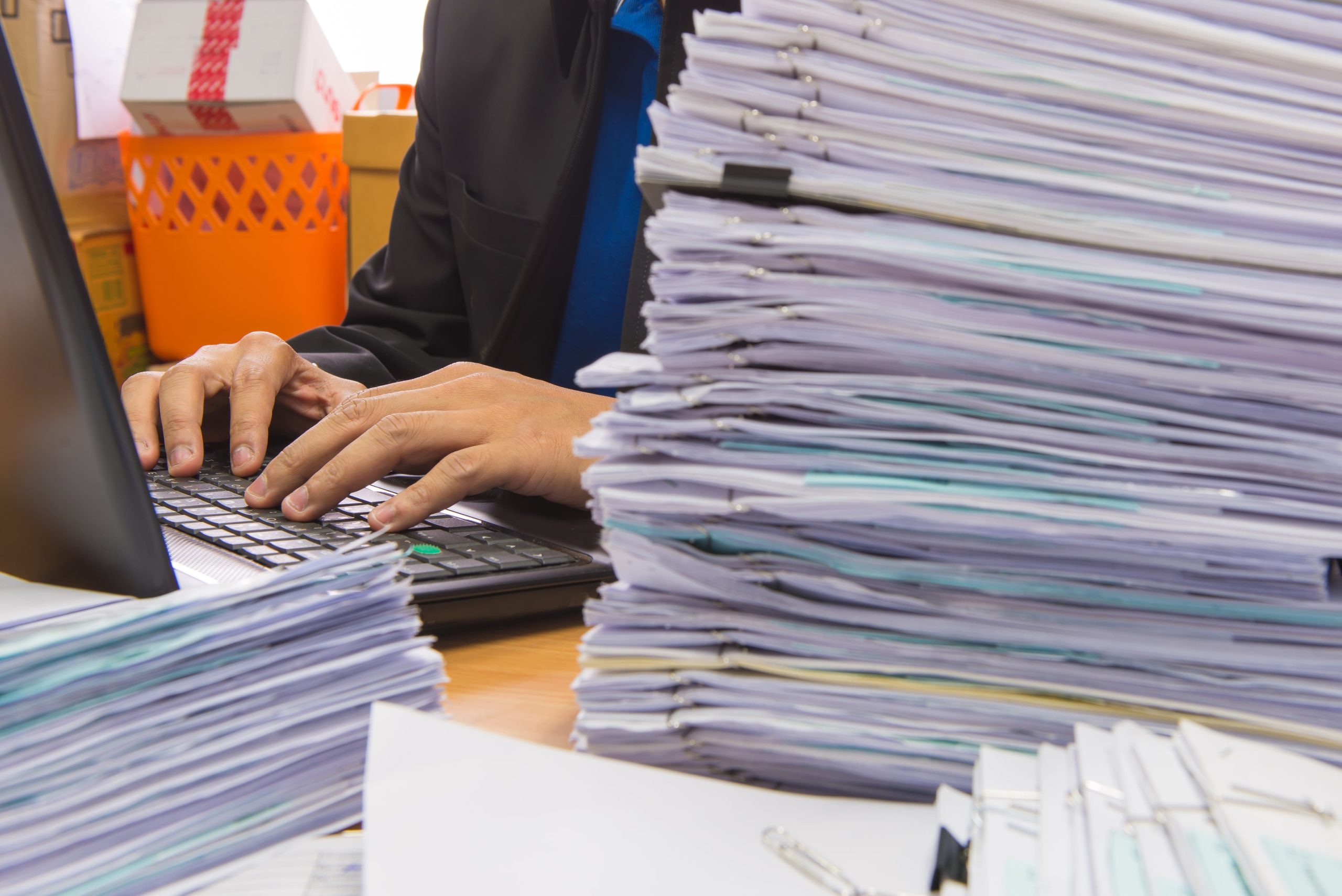 Imagen de un trabajador en su puesto con el escritorio lleno de papeles.