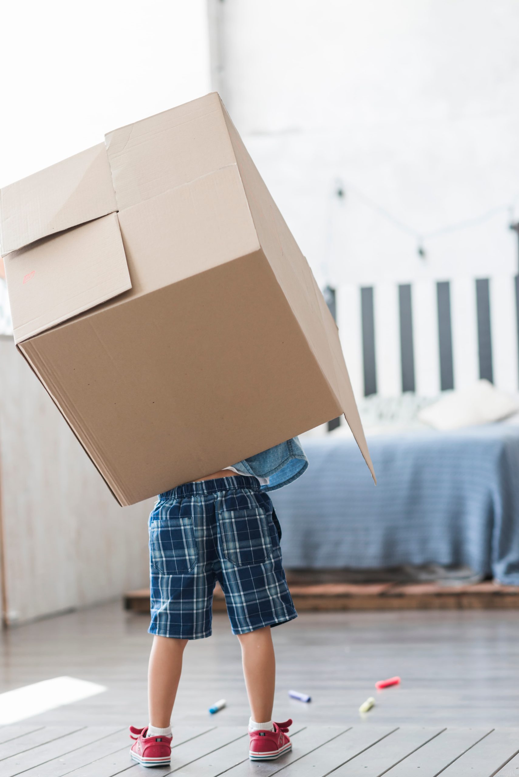 Niño en su habitación cargando una caja de mudanzas